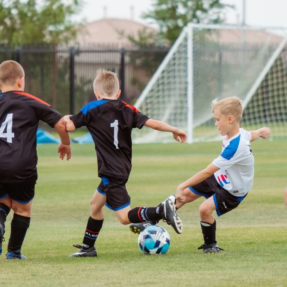 Kids playing football on an outdoor pitch